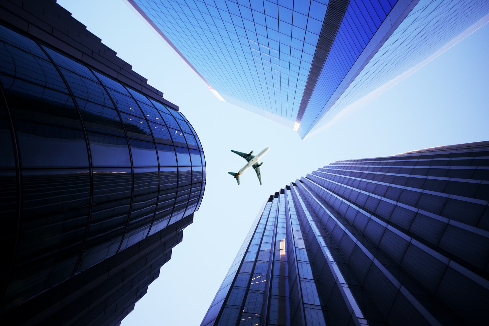 white airplane flying over the high rise building during daytime