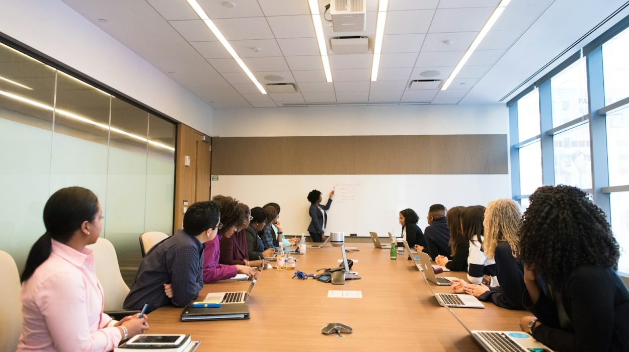 people on conference table looking at talking woman